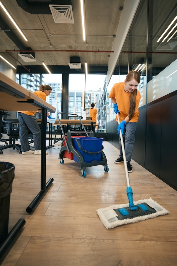 Reinigungsteam wischt den Boden in einem modernen Büro.